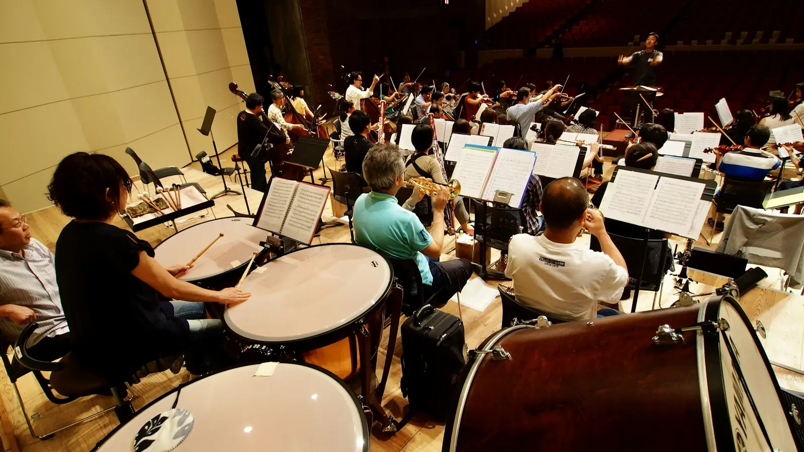 Una orquestra assajant a l’escenari, vista des de darrere dels timbals